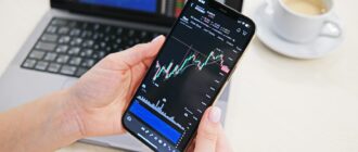 a person holding a cell phone in front of a laptop